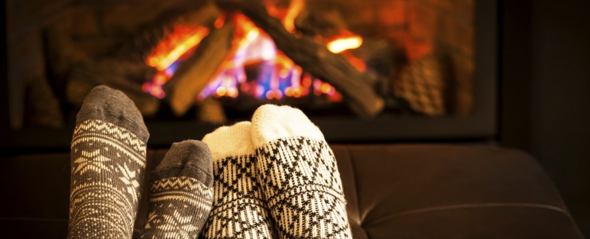 Close up couple's socks in front of a fireplace.