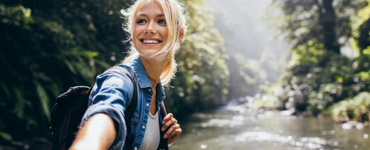 Woman hiking near a stream.