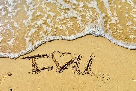 Photo of "I love you" carved into the beach sand.